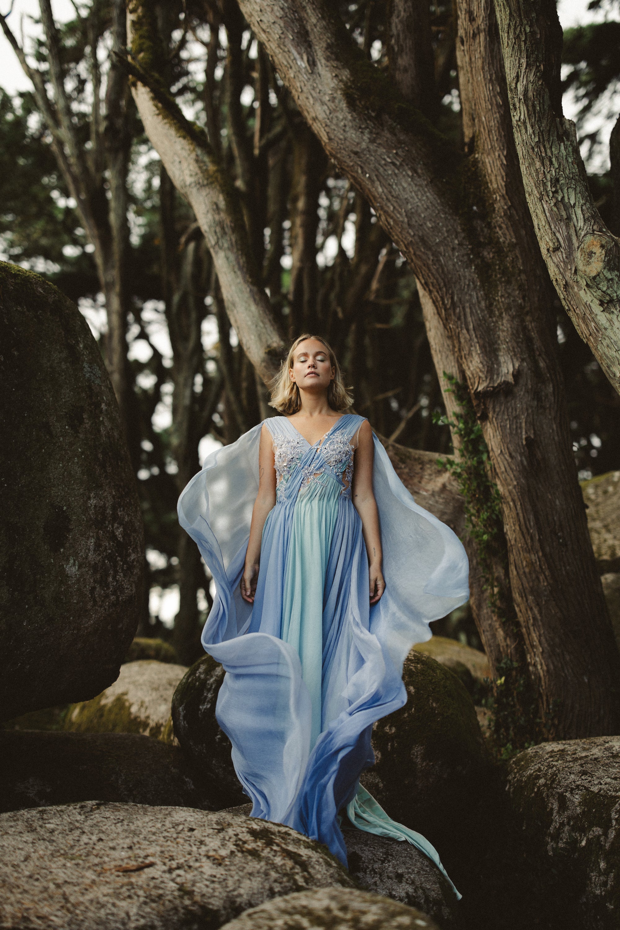 Aéliea whimsical wedding dress full-length view — airy silhouette with flowing skirt and beaded lace bodice among forest trees — MYWONY Bridal
