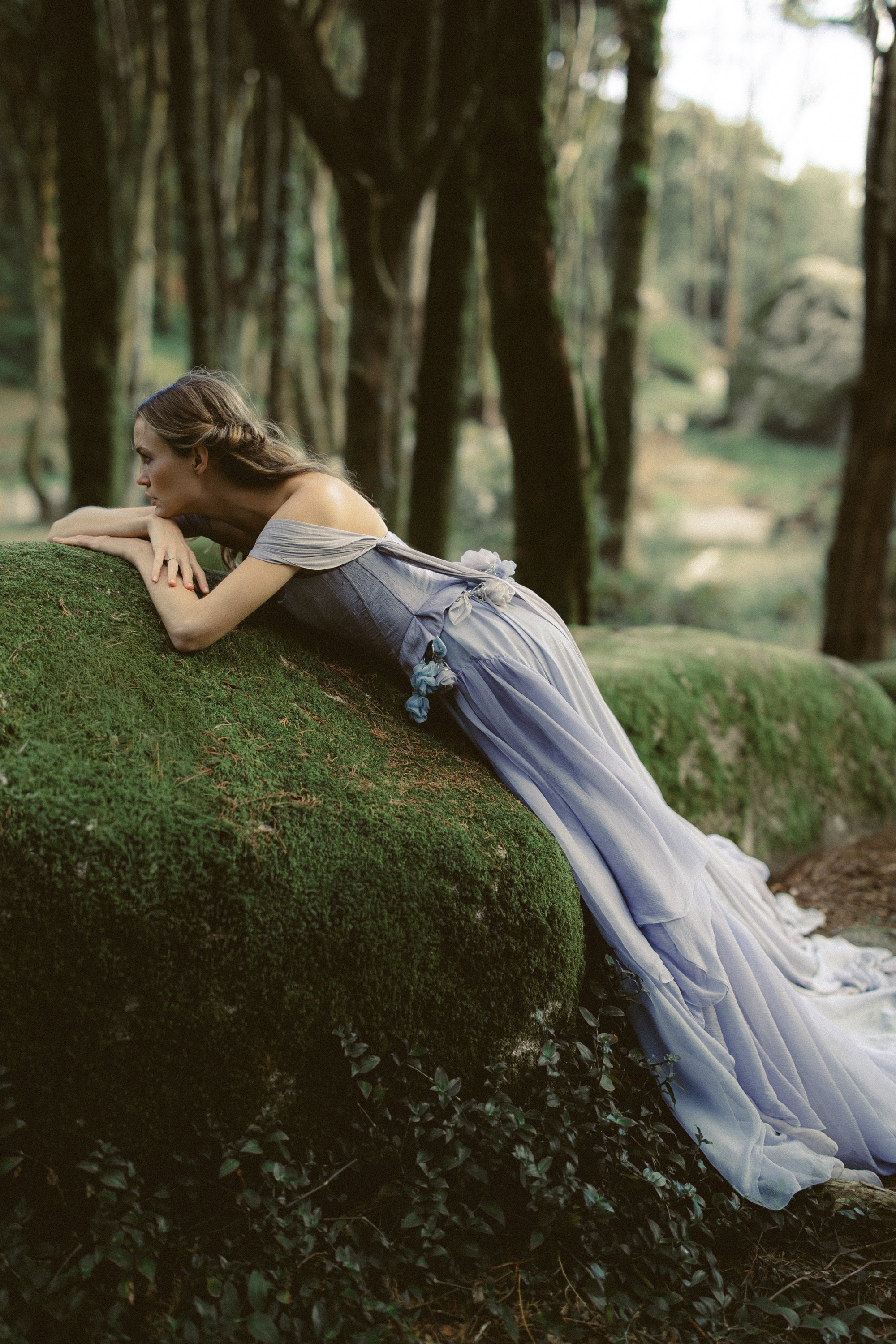 Blooming Belt styled with flowing forest wedding dress, bride leaning on mossy rock in enchanted woodland by MYWONY