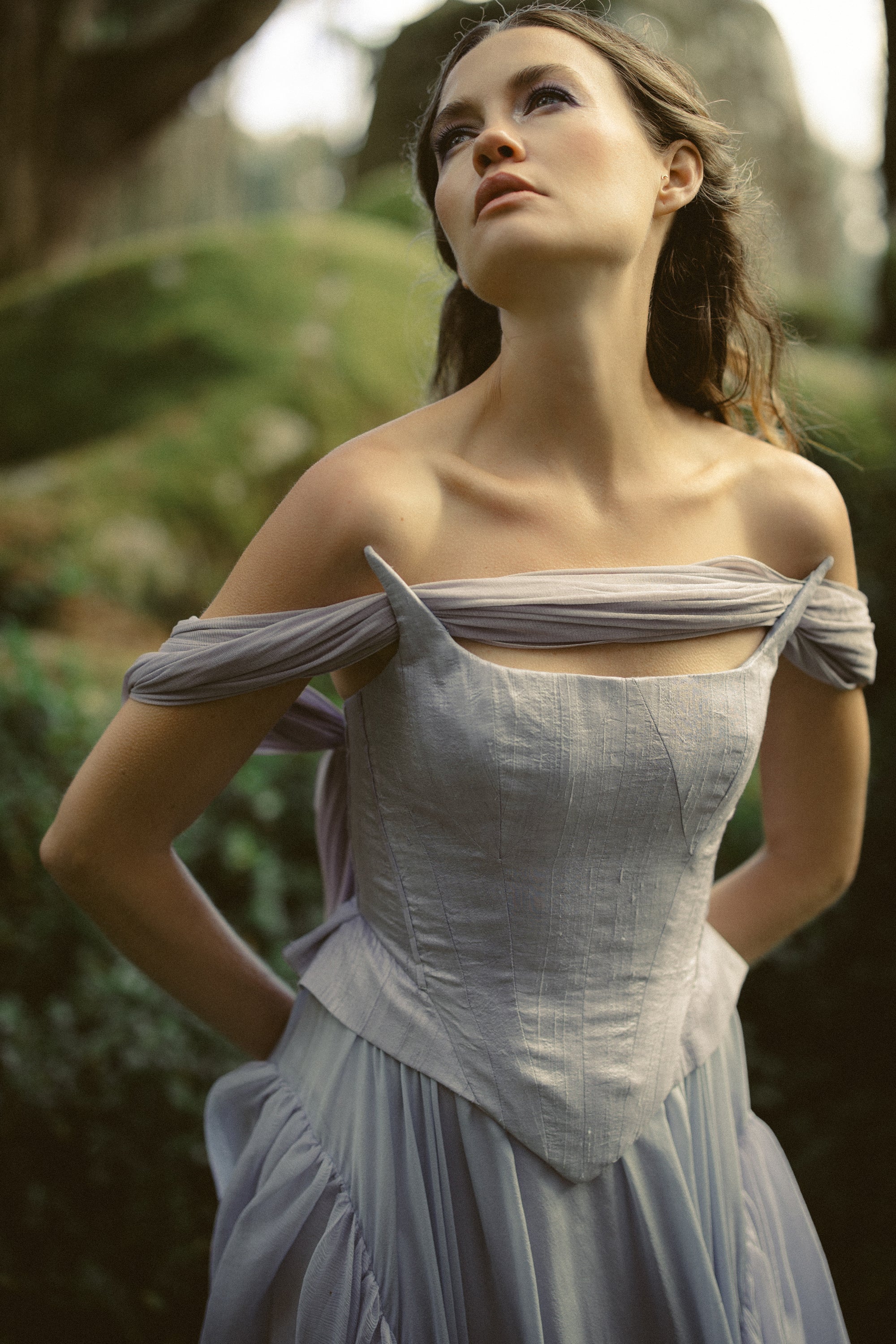 Faelynne romantic silk wedding dress by MYWONY — close-up portrait of off-shoulder corset bodice with organza appliqués in a forest garden setting