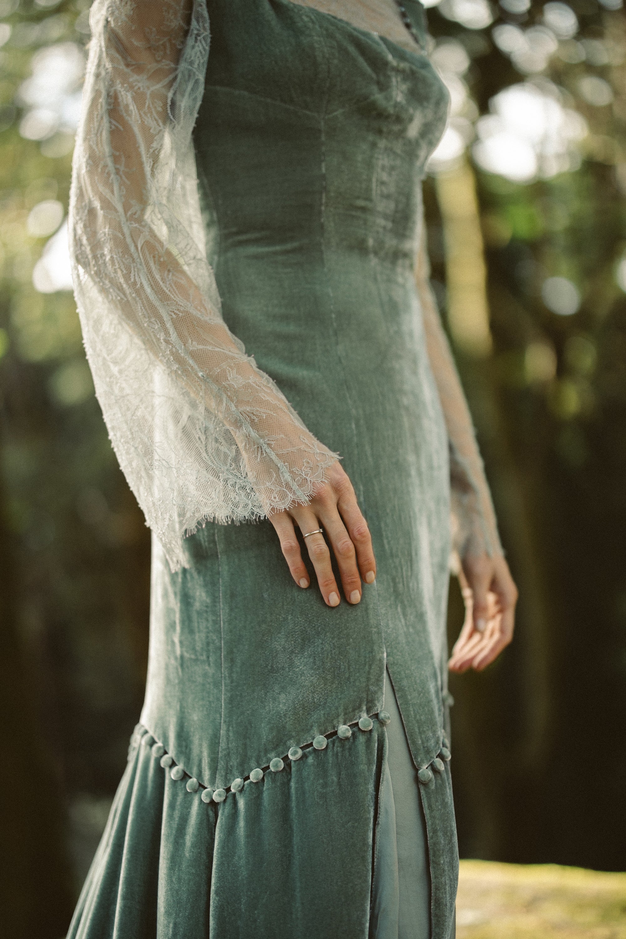 Close-up detail of the Miryelle dress bodice, showcasing the contrast between the plush sage green silk velour and the delicate floral lace underlay.