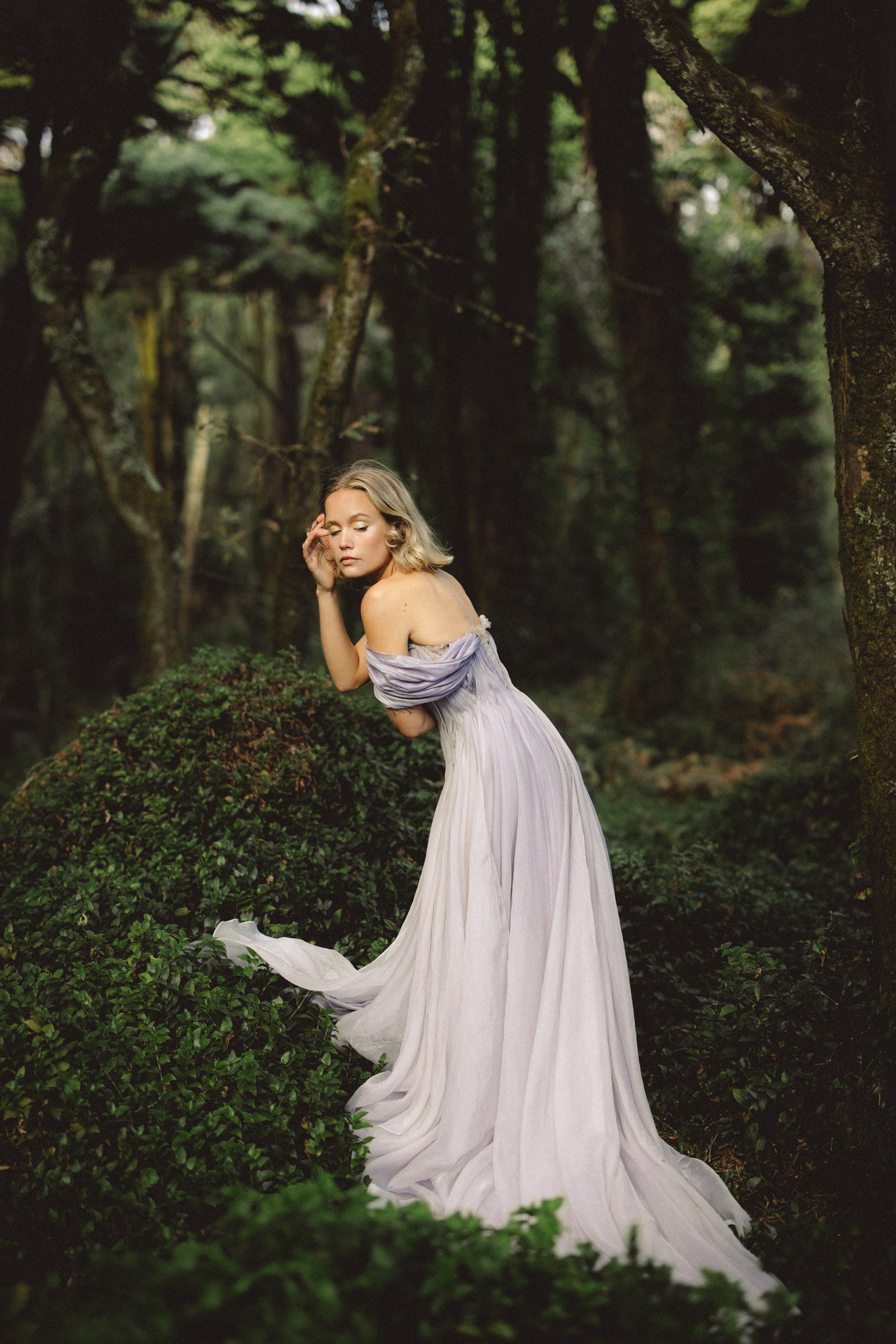 Silynne ethereal wedding gown bride seated among lush forest greenery with silk organza skirt cascading down — MYWONY Bridal