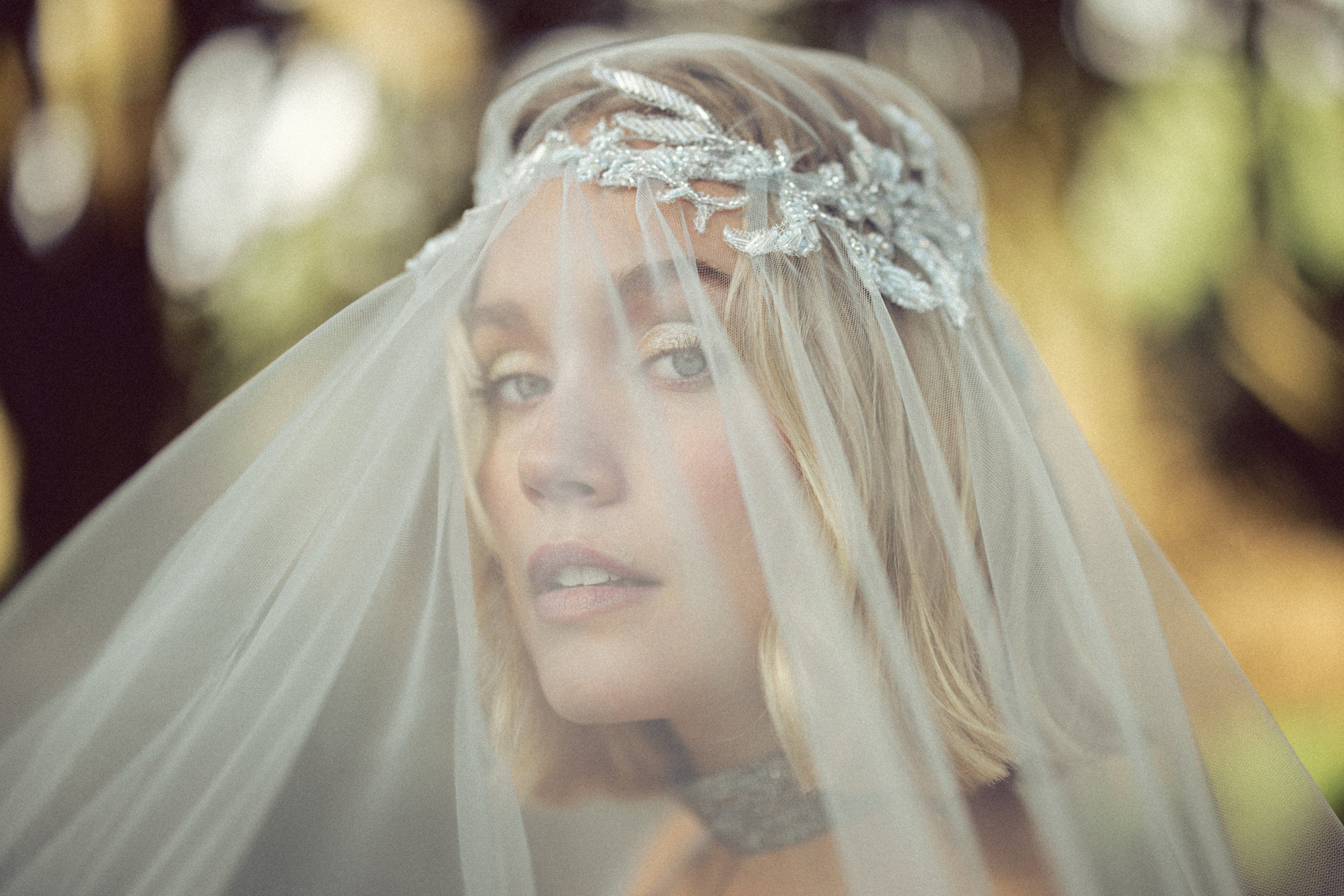 Ethereal bridal portrait through Vea Veil blue tulle by MYWONY, close-up showing beaded lace headpiece crown detail for romantic custom wedding look