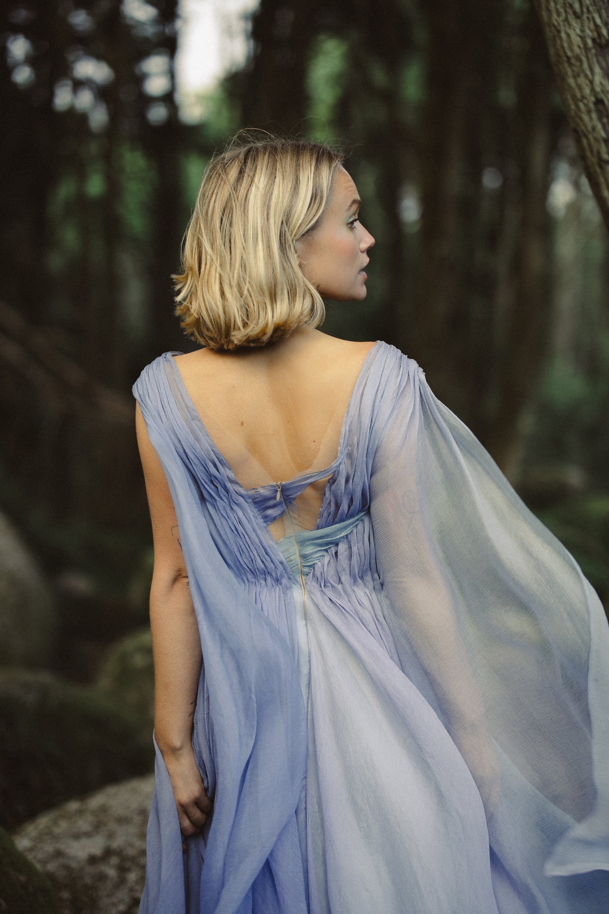 Aéliea romantic wedding dress back view — open-back design with airy gathered fabric and multicolored pleating in forest setting — MYWONY Bridal