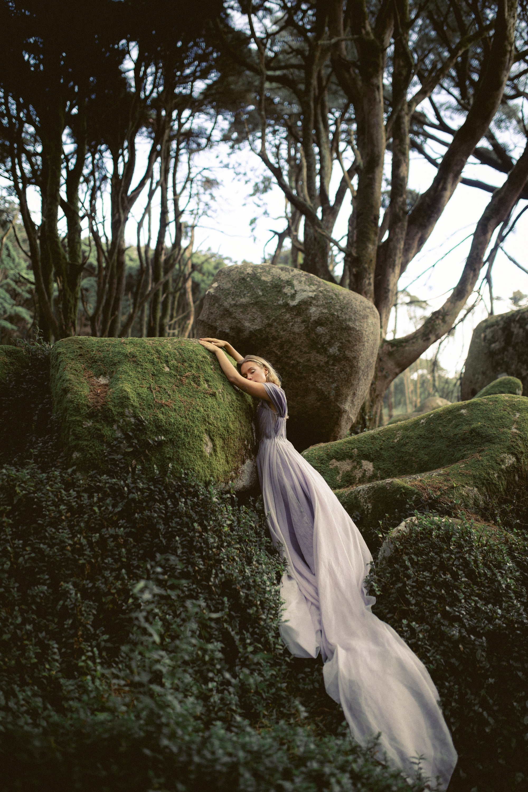 Silynne romantic wedding dress with flowing silk organza skirt draped over moss-covered rocks in enchanted forest setting — MYWONY Bridal